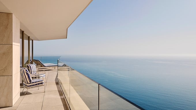 Expansive terrace overlooking the ocean, furnished with loungers and striped chairs.