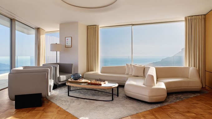 Light-filled living room with modern white seating and floor-to-ceiling sea views.