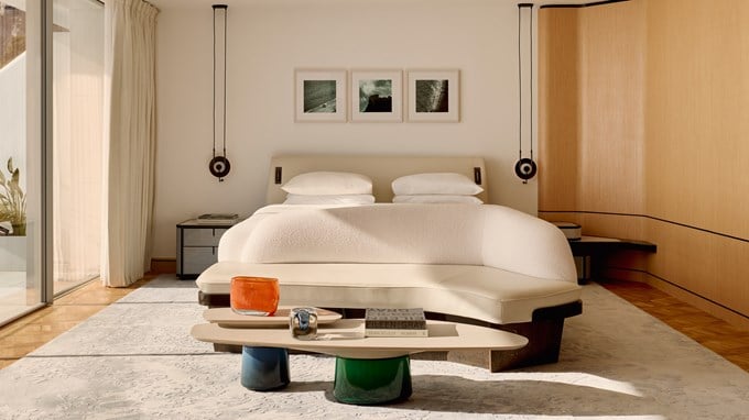 Serene bedroom with sculptural furnishings and sea-facing glass doors.