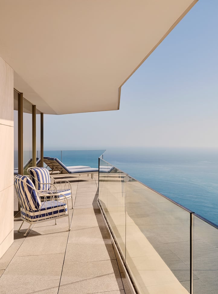 Private terrace with striped lounge chairs and panoramic sea view.