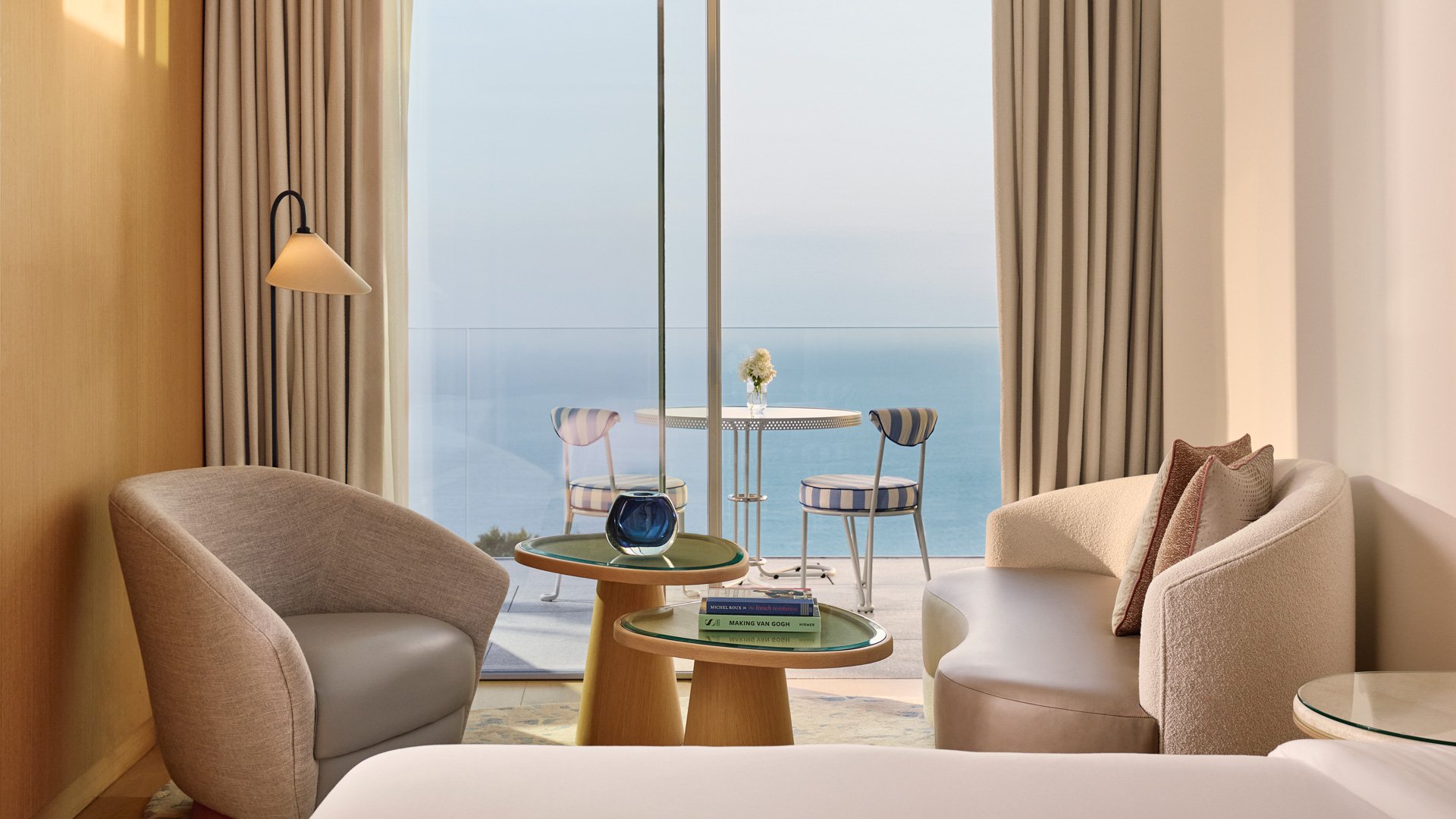 Modern seating area with ocean-view balcony featuring two striped chairs and a small table.