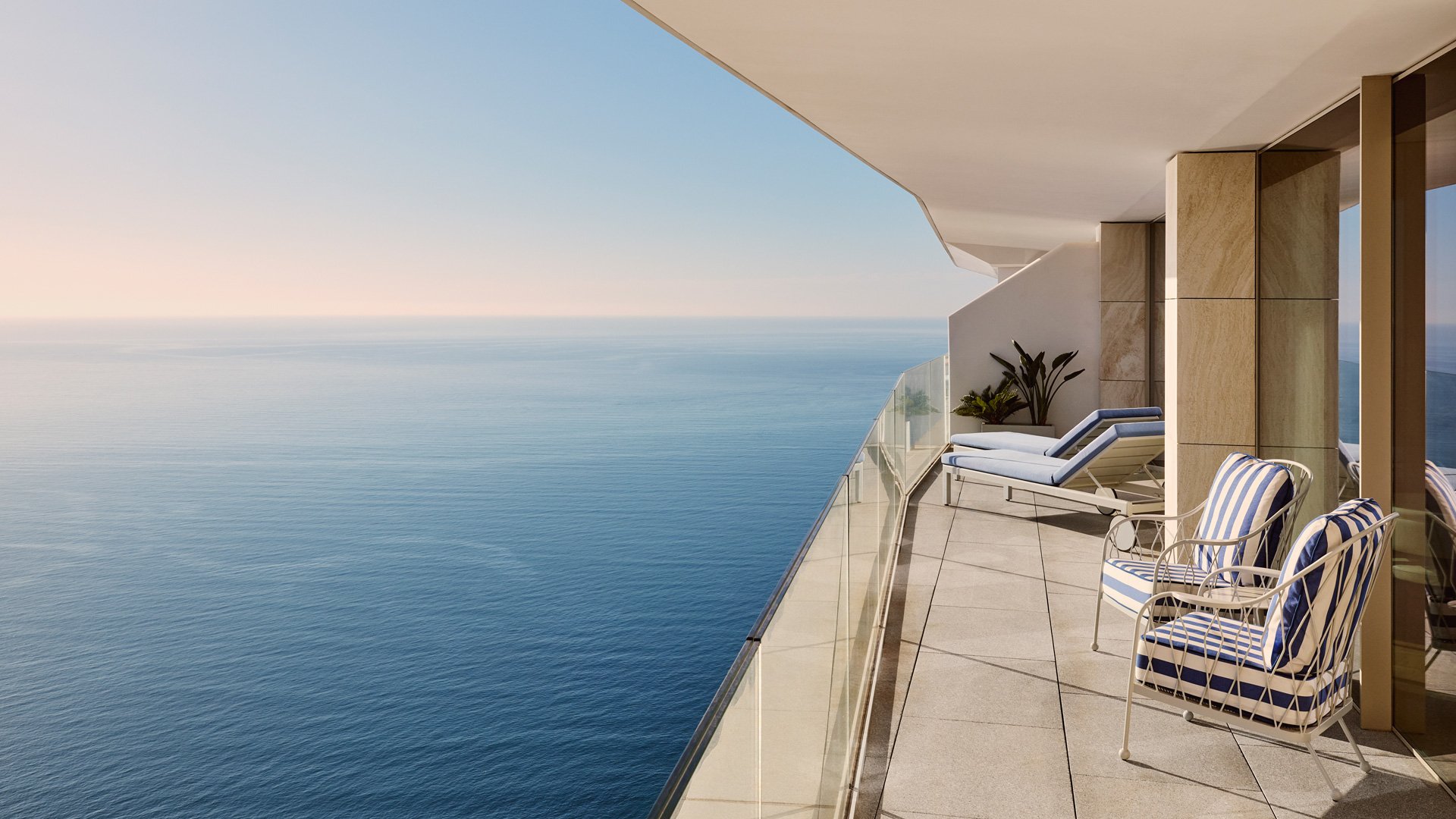 Wide balcony with striped lounge chairs and uninterrupted views over the open sea.