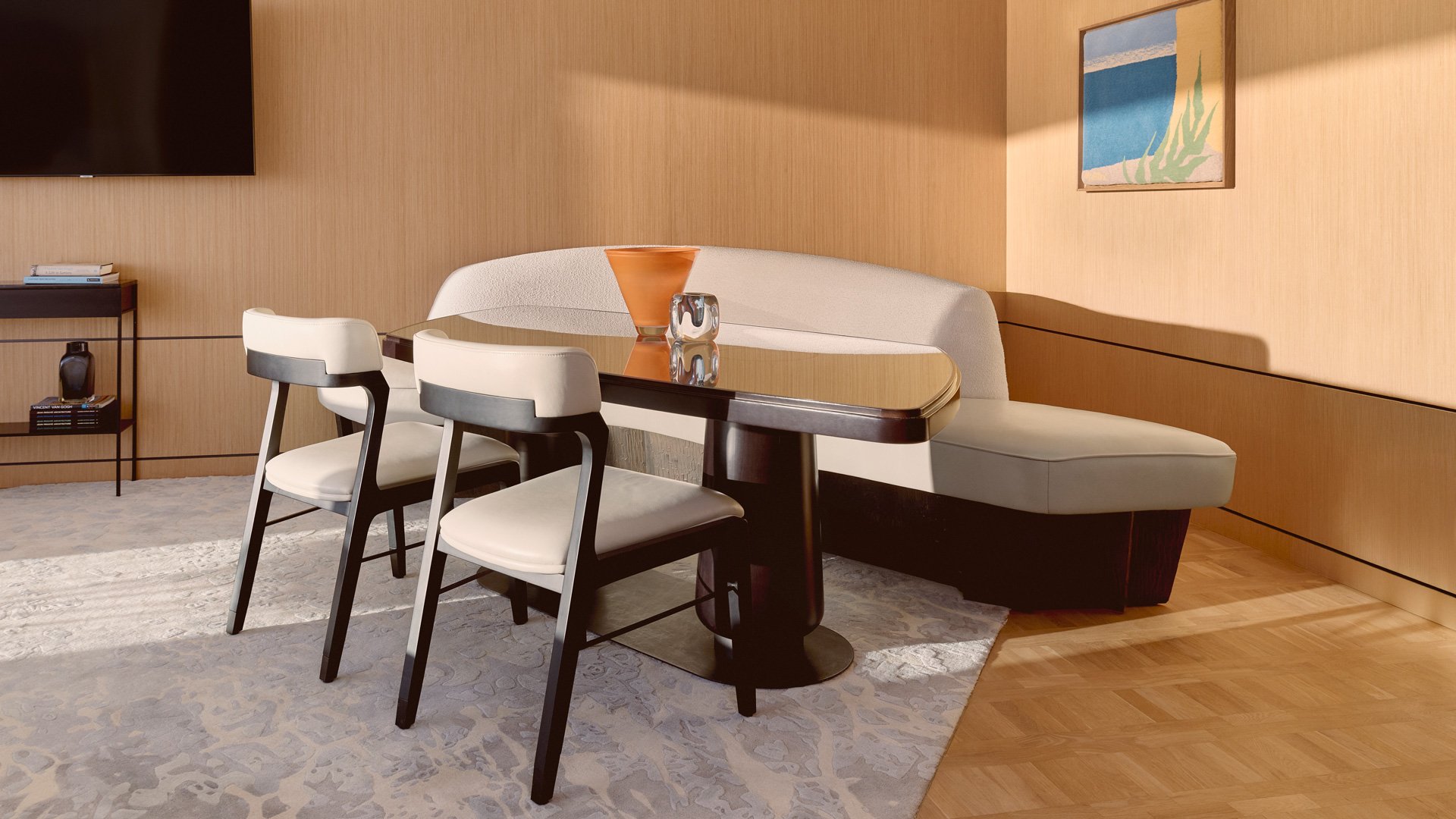 Dining nook with upholstered bench and two chairs, beside a wood-panelled wall.