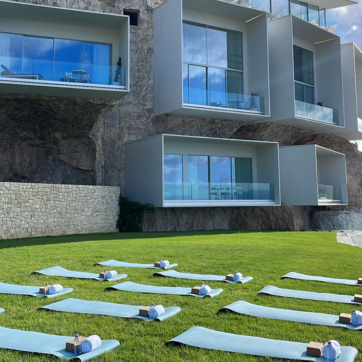 Blue yoga mats on a lawn in front of The Maybourne Riviera