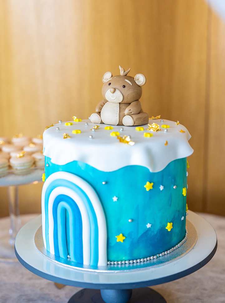 A children cake with blue icing and a bear on top of it